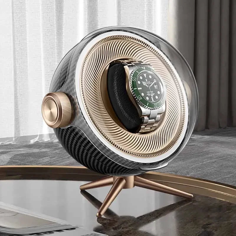 Luxury automatic watch winder with gold accents holding a stainless steel wristwatch